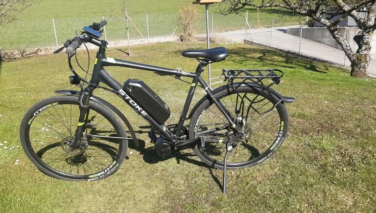 Vélo électrique avec sa batterie fixée sur le cadre, garé dans l’herbe